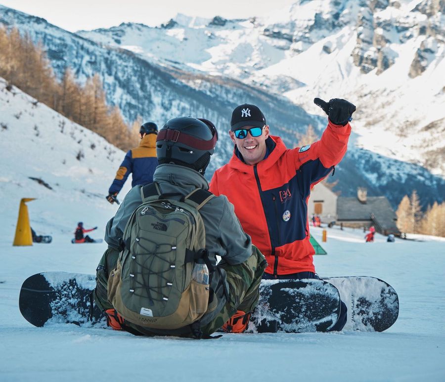 Maestro di snowboard sorridente con un allievo durante una lezione ad Alpe Ciamporino, San Domenico di Varzo